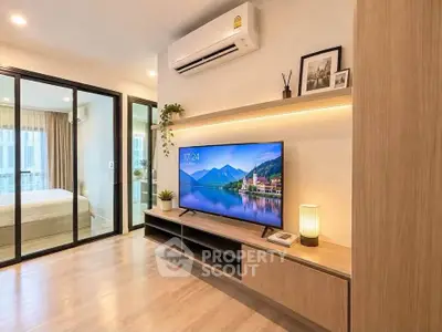 Modern living room with sleek TV unit and air conditioning, adjacent to a cozy bedroom.