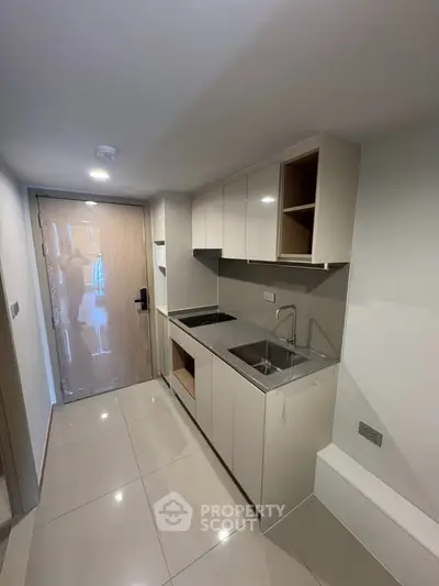 Modern compact kitchen with sleek cabinetry and integrated sink in a stylish apartment.