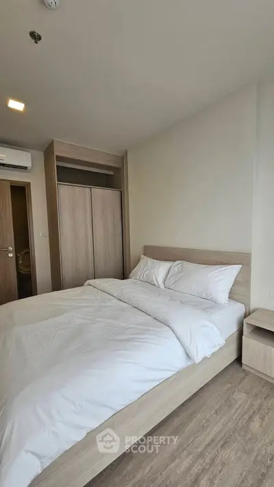 Spacious modern bedroom with wooden flooring and sleek wardrobe design.