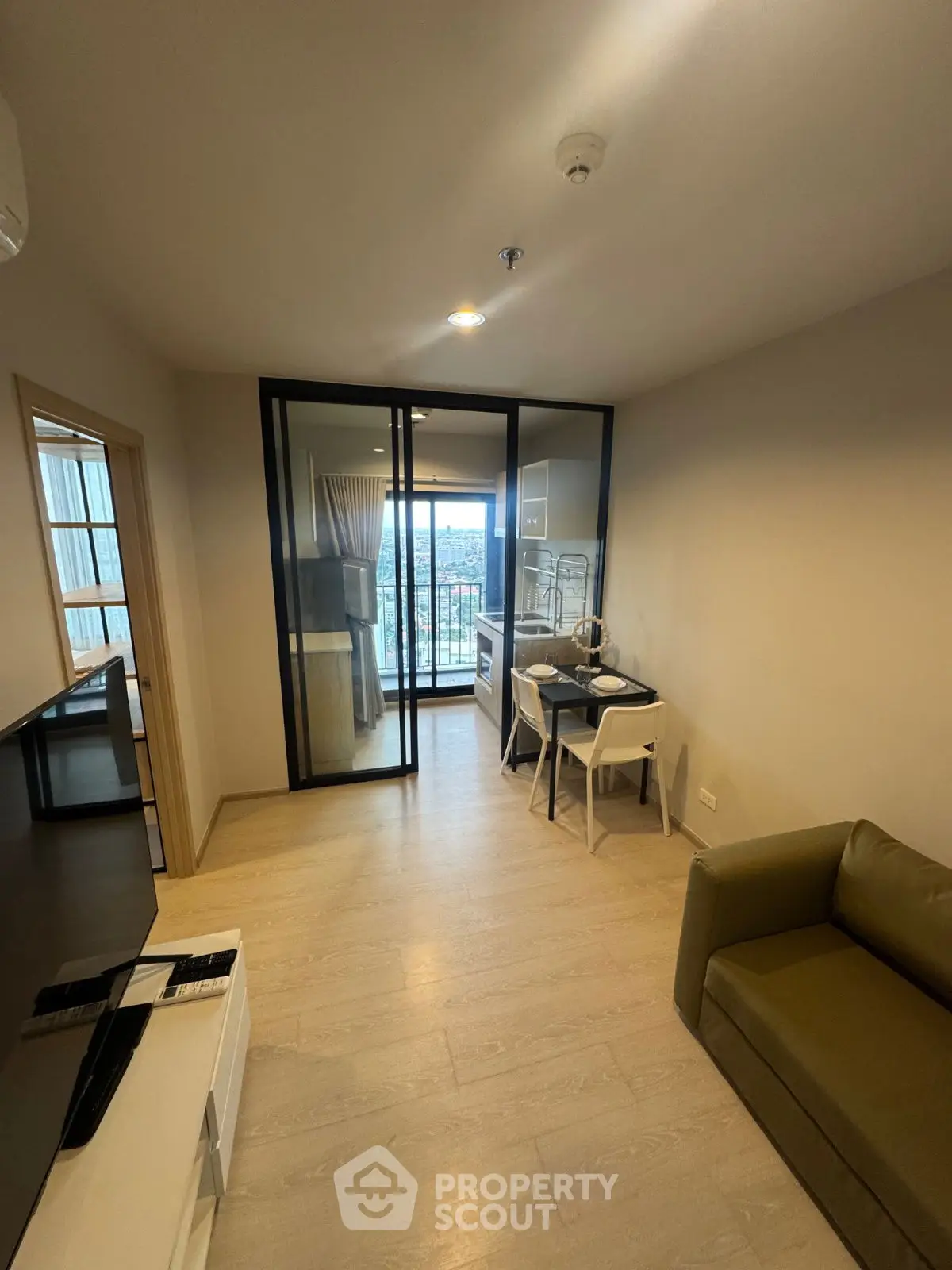 Modern living room with glass doors leading to a balcony offering a stunning city view.
