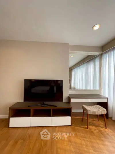 Modern living room with sleek TV stand and stylish furniture, featuring natural light and elegant decor.