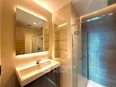 Modern bathroom with sleek design, featuring a large mirror, glass shower, and elegant lighting.