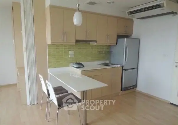 Modern kitchen with sleek cabinetry and compact dining area in open layout apartment.
