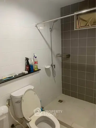 Modern bathroom with shower and toilet in sleek tiled design.