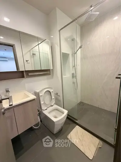 Modern bathroom with glass shower and sleek vanity in contemporary apartment.