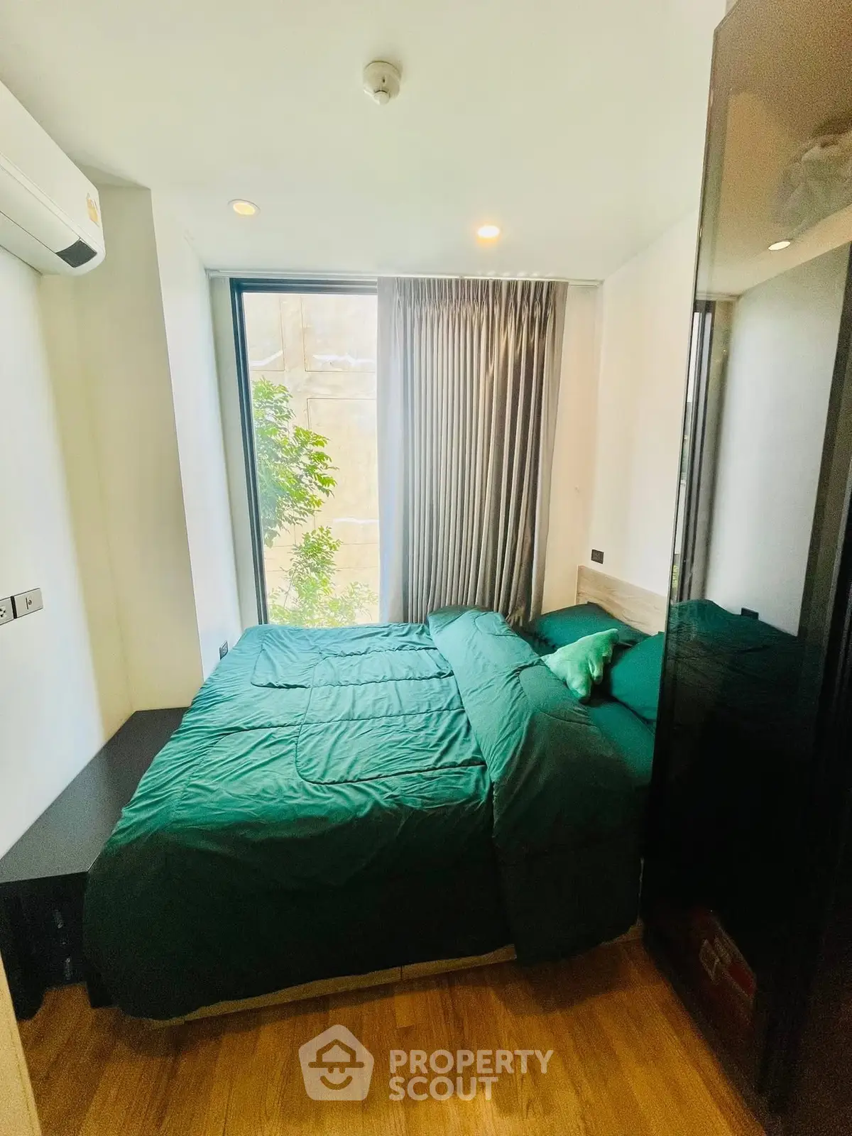Cozy bedroom with large window and green bedding in modern apartment