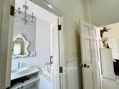 Elegant bathroom with chandelier and vintage mirror, showcasing luxury design.