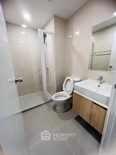 Modern bathroom with sleek fixtures and spacious shower in contemporary apartment.