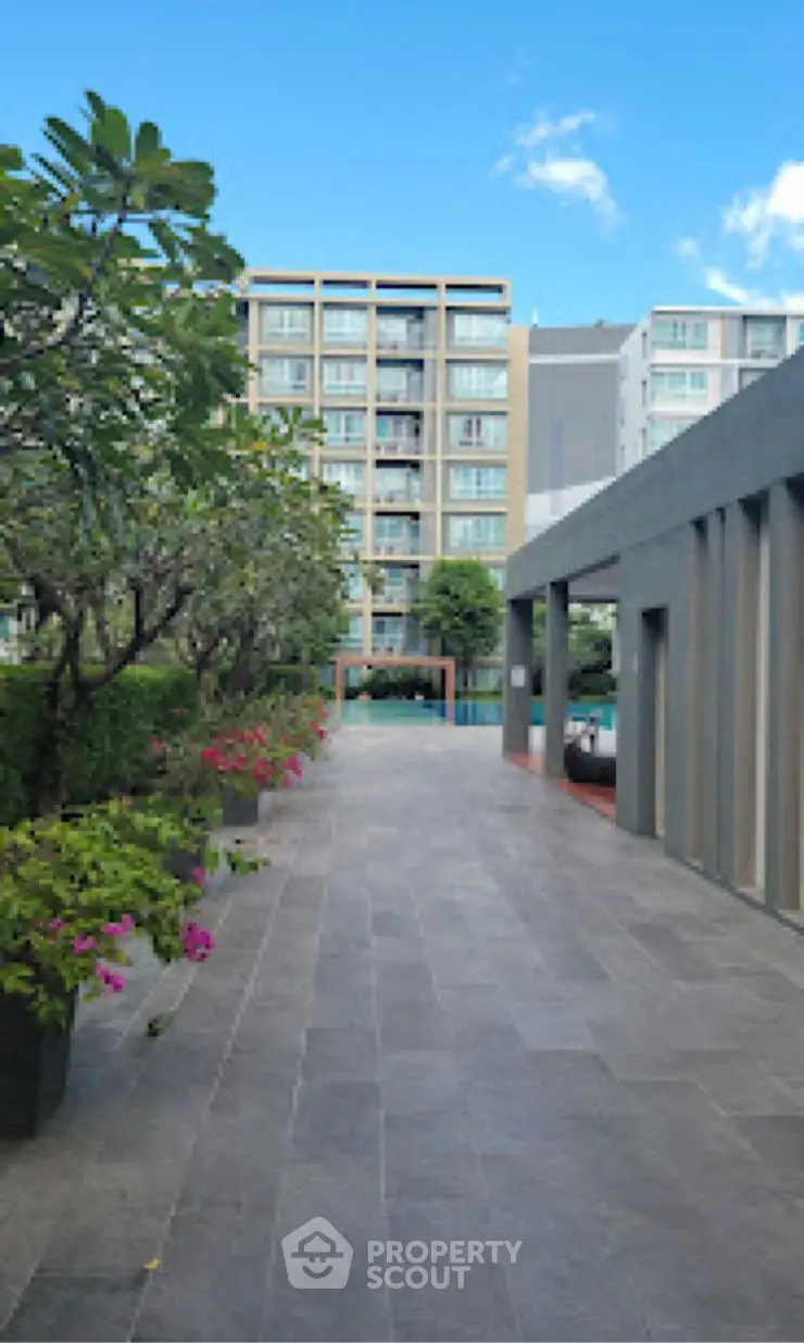 Modern apartment building with spacious walkway and lush greenery