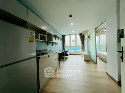 Modern open-layout apartment with sleek kitchen and bright living area, featuring large windows and stylish decor.