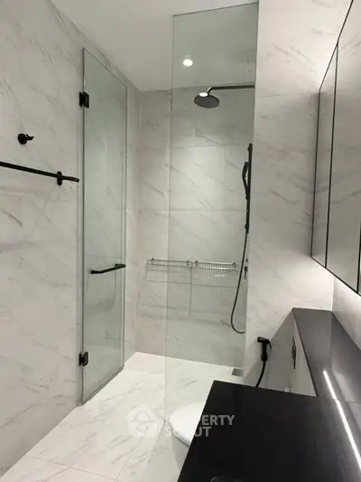 Luxurious modern bathroom with sleek glass shower and elegant marble tiles.