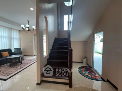 Elegant staircase in a modern home with stylish living room and natural light.