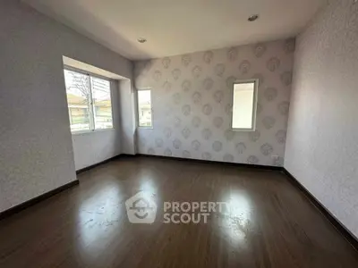 Spacious empty room with elegant wallpaper and wooden flooring, perfect for customization.
