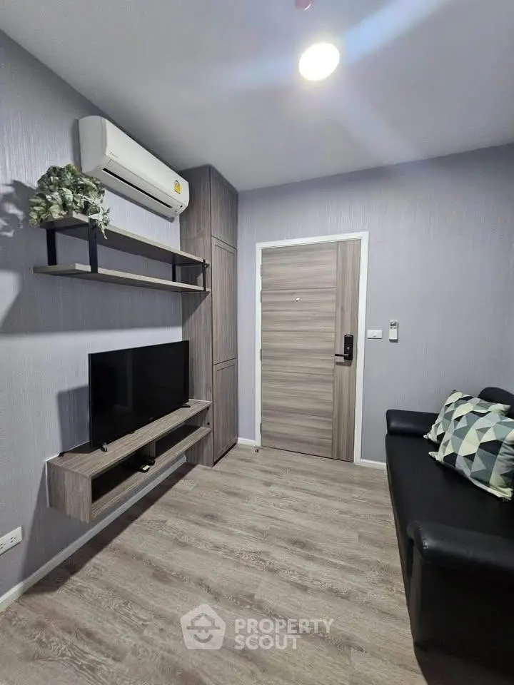 Modern living room with sleek design, featuring a wall-mounted TV and air conditioning unit.