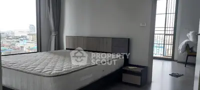 Modern bedroom with city view and large windows, featuring a comfortable bed and minimalist decor.