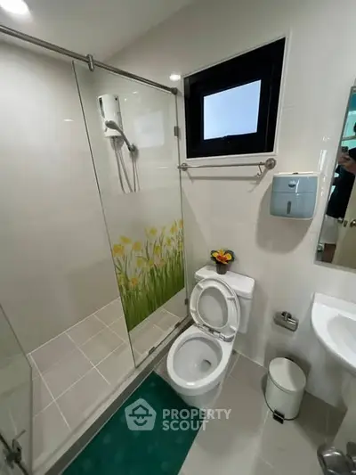 Modern bathroom with glass shower and floral design, featuring sleek fixtures and bright lighting.