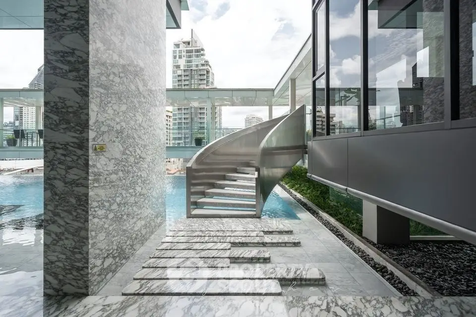 Luxurious modern building with stunning pool and spiral staircase, offering breathtaking city views.