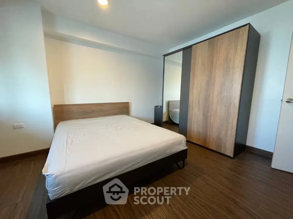 Modern minimalist bedroom with wooden flooring and sleek wardrobe