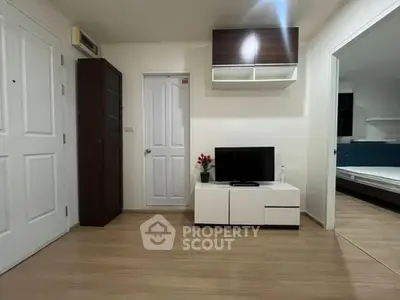 Modern living room with sleek furniture and wooden flooring, adjacent to a cozy bedroom.
