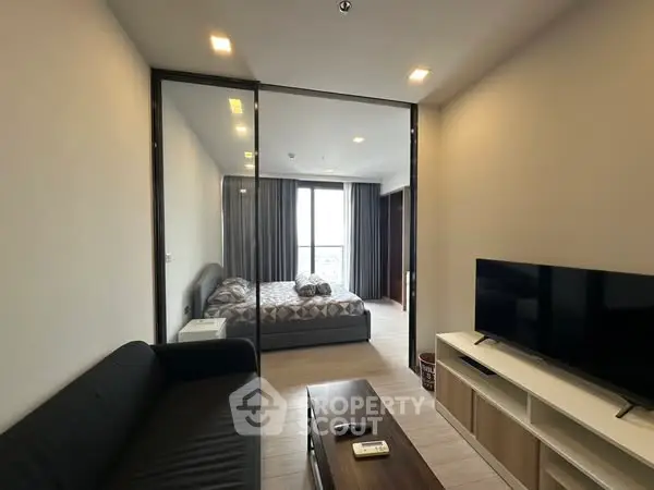 Modern apartment with cozy living room and bedroom, featuring sleek furniture and natural light.