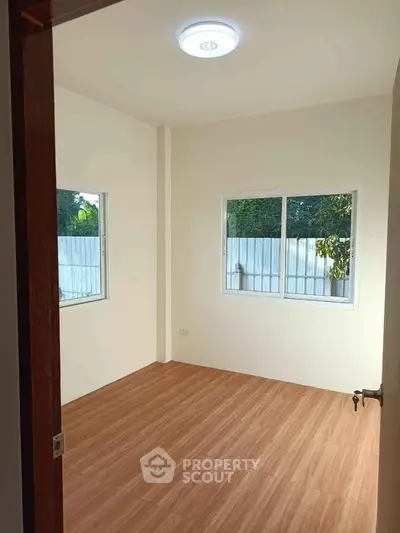 Bright empty room with wooden flooring and large windows
