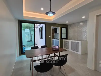 Modern dining area with sleek table and chairs, adjacent to stylish kitchen and outdoor view.