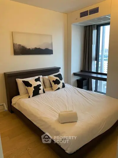 Modern bedroom with city view, featuring stylish decor and natural light.