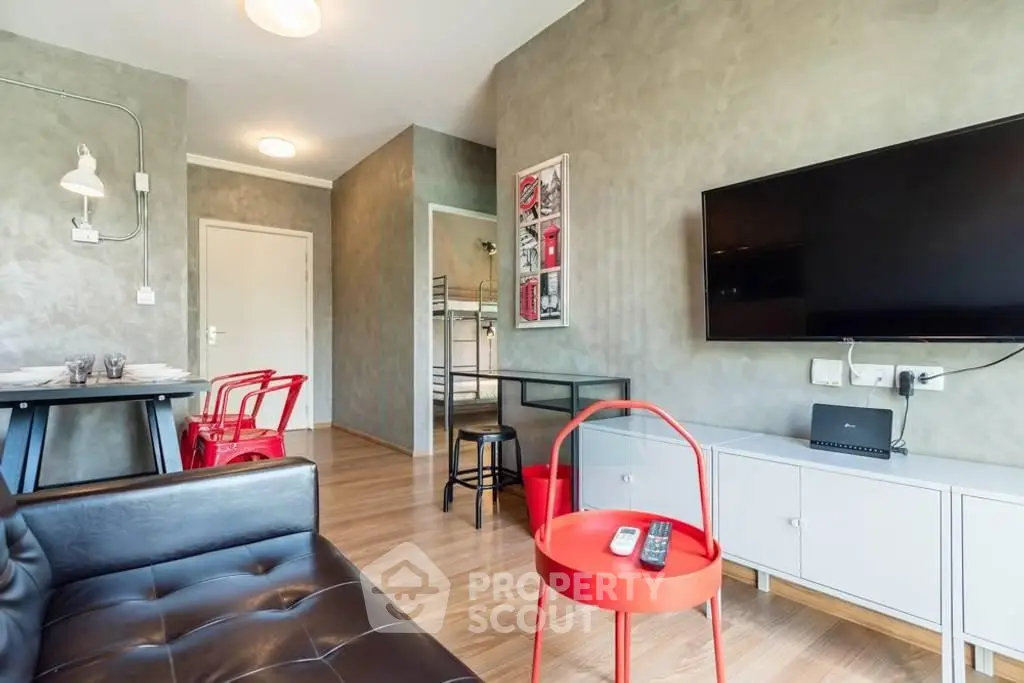 Modern living room with sleek furniture and wall-mounted TV, featuring stylish red accents and wooden flooring.