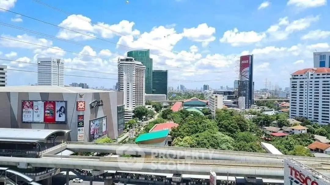Stunning cityscape view showcasing modern high-rise buildings and lush greenery under a bright blue sky.