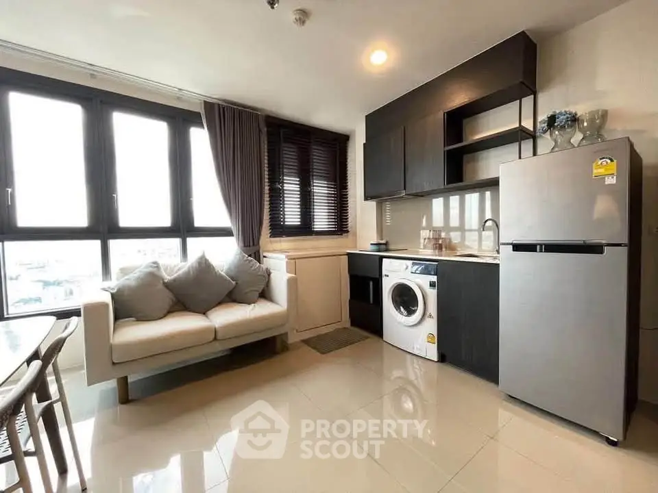 Modern living room with kitchen featuring sleek appliances and cozy seating area.