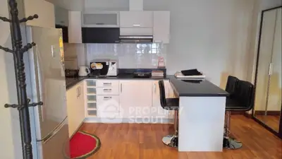 Modern kitchen with sleek white cabinets and breakfast bar in cozy apartment.