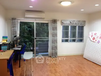Spacious room with wooden flooring and large windows overlooking greenery