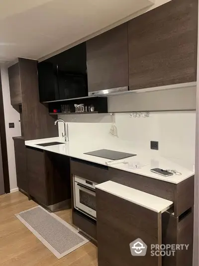 Modern kitchen with sleek dark cabinets and built-in oven in stylish apartment