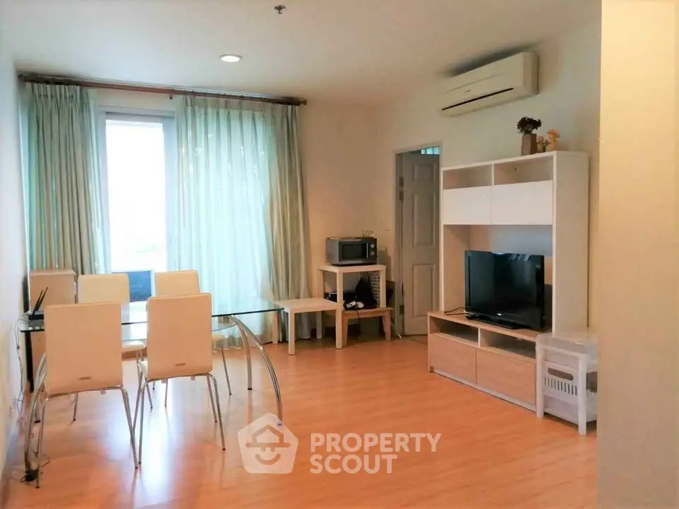 Modern living room with dining area, TV, and air conditioning in a bright apartment.