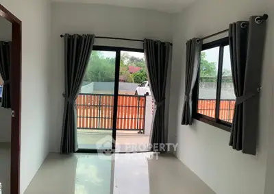 Bright room with sliding glass doors leading to a patio, featuring modern gray curtains.