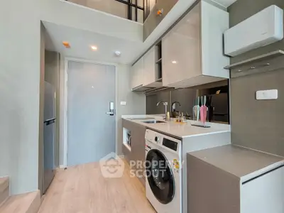 Modern compact kitchen with washing machine and sleek cabinetry in a stylish apartment.