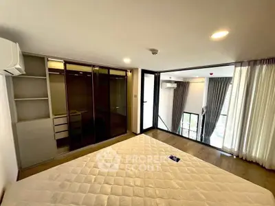Spacious modern bedroom with large windows and built-in wardrobe in a stylish apartment.