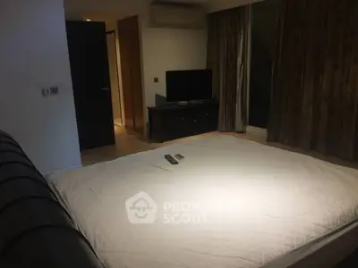 Spacious bedroom with modern decor and large bed, featuring a sleek TV setup.