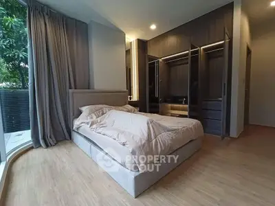 Spacious bedroom with elegant design and large windows overlooking greenery, featuring a modern wardrobe.