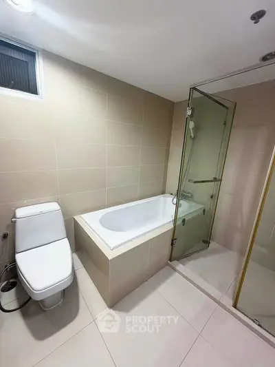 Modern bathroom with bathtub and glass shower enclosure in a sleek design.