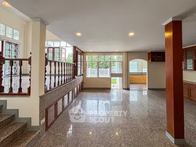 Spacious open-plan living area with large windows and elegant staircase