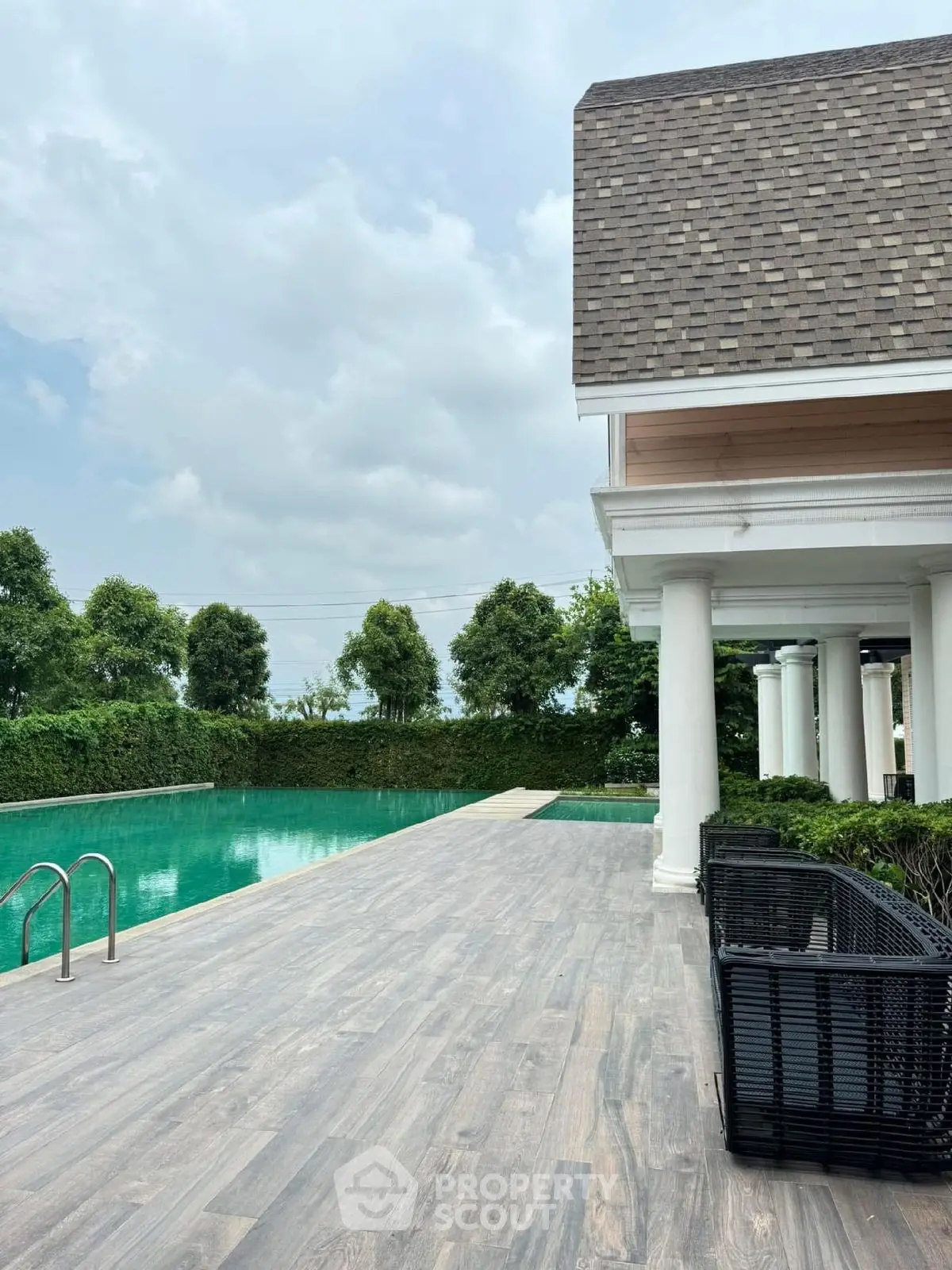 Luxurious poolside view with elegant architecture and lush greenery, perfect for relaxation and entertainment.