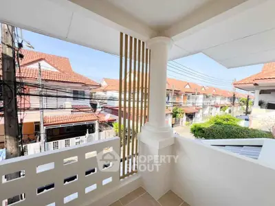 Charming balcony view of suburban neighborhood with red-tiled roofs and clear blue sky.