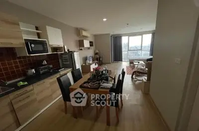 Spacious open-plan living room with modern kitchen and dining area, featuring large windows and city views.