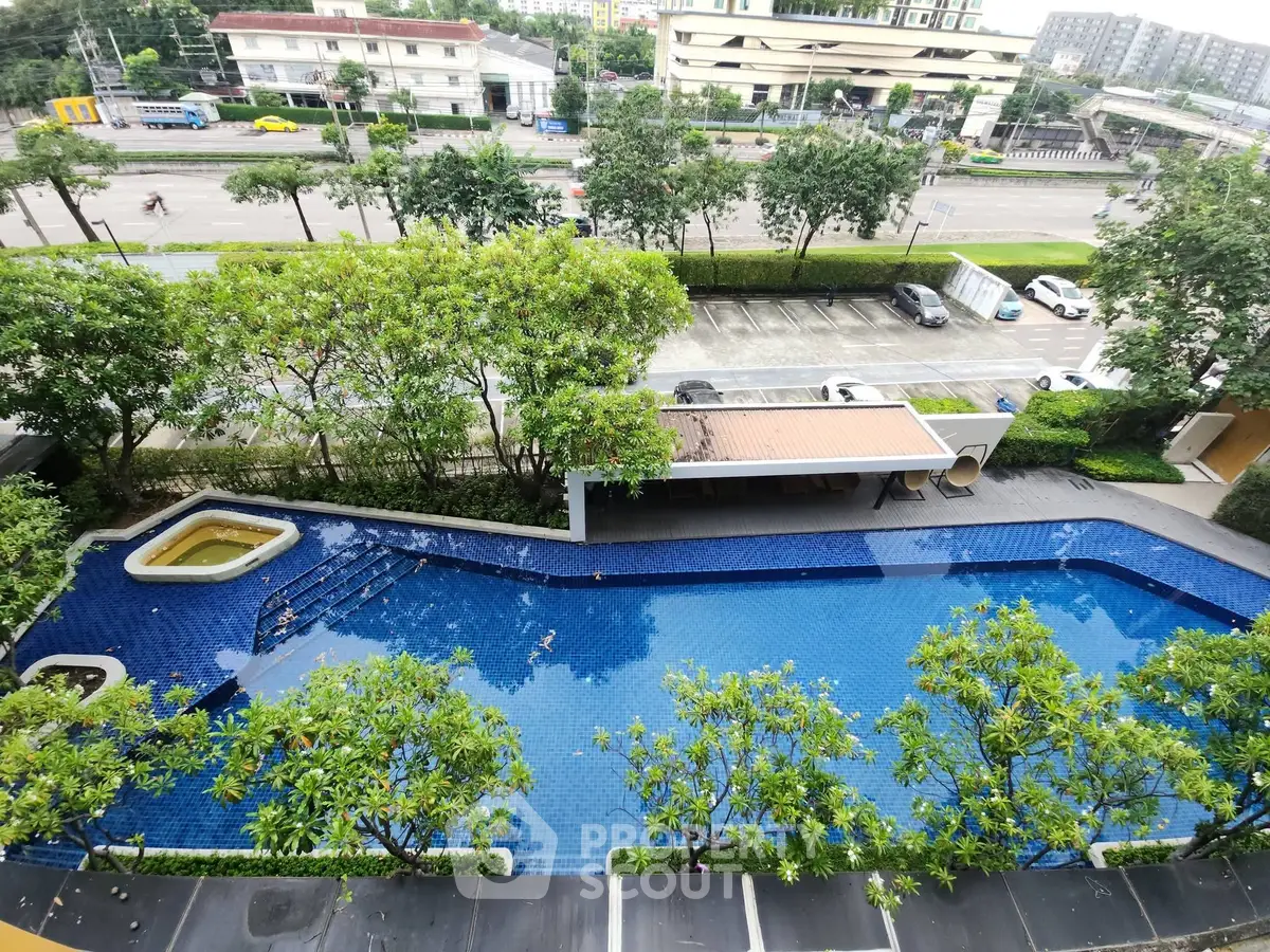 Stunning aerial view of a luxurious residential swimming pool surrounded by lush greenery.