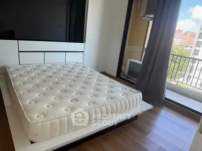 Spacious bedroom with large window and balcony access, featuring a comfortable mattress and modern design.