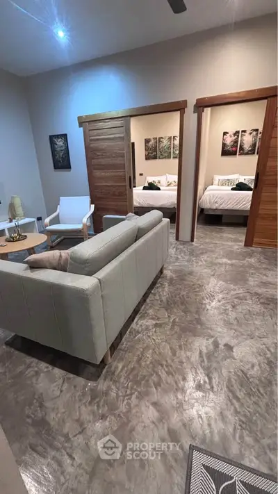 Modern living room with stylish furniture and sliding wooden doors leading to a cozy bedroom.