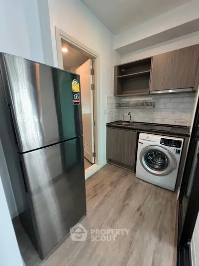 Modern kitchen with stainless steel fridge and washing machine in compact layout