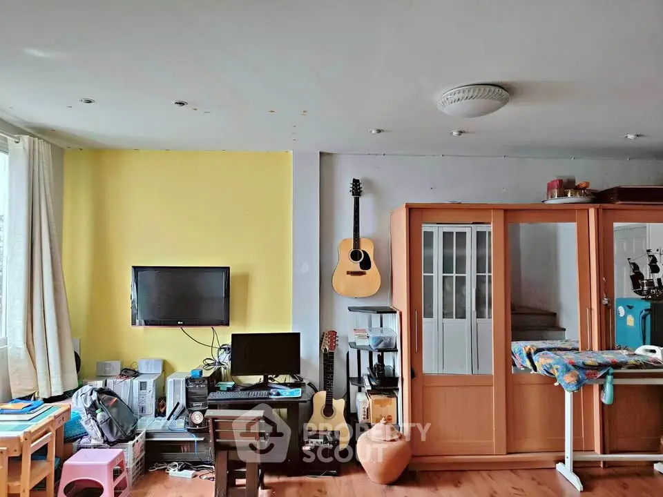 Cozy living room with vibrant yellow accent wall, guitar decor, and modern entertainment setup.