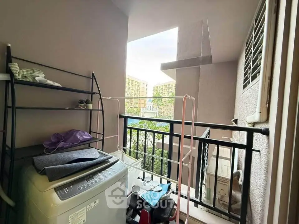 Compact balcony with washing machine and drying rack in urban apartment